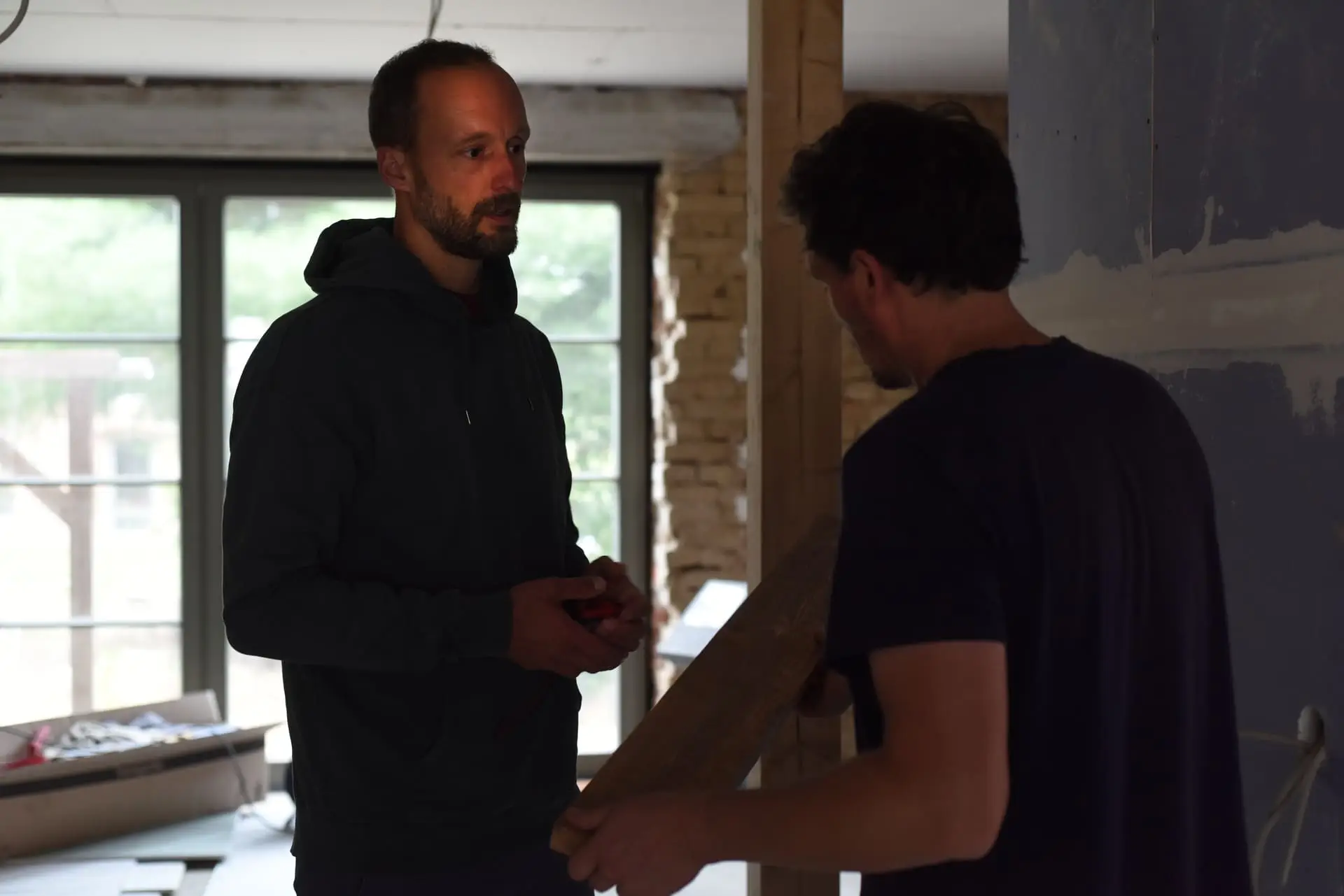 Projektsteuerer Erik Pfauth auf der Baustelle im Gespräch mit einem Handwerker.